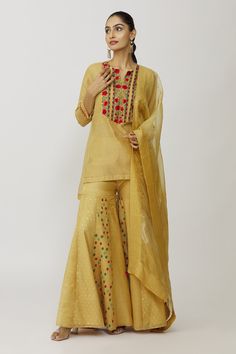 Gold kurta with hand embroidered yoke and sleeves. Comes with bustier, gharara and dupatta.
Components: 4
Pattern: Embroidery
Type Of Work: Floral
Neckline: Kurta: Notched, Bustier: Scoop
Sleeve Type: Kurta: Three quarter, Bustier: Sleeveless
Fabric: Tissue, Cotton Lycra, Voile, Organza
Color: Gold
Other Details: 
Panelled gharara
Approx weight (in gms): 700
Closure: Gharara: Elastic
Occasion: Work - Aza Fashions Tissue Kurta, Embroidery Floral, Pattern Embroidery, Set For Women, Aza Fashion, Sleeve Type, Floral Embroidery, Three Quarter, Hand Embroidered