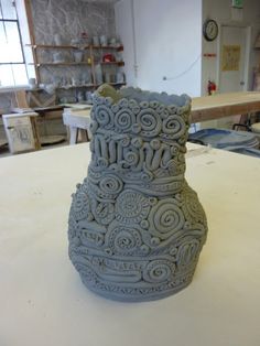 a ceramic vase sitting on top of a table in a room filled with other items