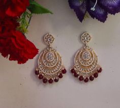 Metal = Gold Plated Occasion = Wedding ,Party Wear, Bridal Color = White and Red Size = Earrings Size - 3.5 Inches(approx) Closure = Screw Back 100% Satisfaction Guarantee: 1 Year Warranty, Long Lasting Plating, High-Quality Stones Occasion: Perfect choice for any Indian occasion. Care: It is advisable that you keep products away from direct heat, humidity, and moisture. It is best to preserve your jewelry in the box. Keep Away From Water, Spray And Perfumes For Better Look. Free Shipping Worldw Luxury Ruby Jhumkas For Diwali, Luxury Traditional Ruby Jhumkas, Red Chandbali Chandelier Earrings For Wedding, Red Round Jhumkas For Wedding, Wedding Bridal Dangle Earrings With Stone Work, Kundan Chandelier Earrings For Wedding, Red Chandbali Danglers For Wedding, Red Wedding Danglers, Round Meenakari Danglers For Wedding