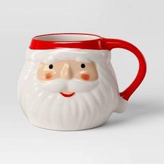 a ceramic mug with a santa face on it's side and a red handle