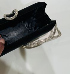 The Black Clutch Purse is a stylish blend of sophistication and glamour. It is crafted with precision and attention to details. This satin evening clutch is a must have addition to your accessory collection. It will glamorize your look and is spacious enough to carry all the essentials. The clutch comes with a detachable chain strap so you can carry it as a clutch or a shoulder bag. Dimensions: (LxW): 7.67 inches x 4.33 inches Material: Satin exterior and interior, Rhinestones Features: Kiss Loc Luxury Embellished Clutch For Cocktails, Modern Silver Clutch For Evening, Luxury Silver Clutch For Cocktail, Luxury Silver Clutch For Cocktail Events, Luxury Silver Cocktail Clutch, Party Clutch With Rhinestones, Black Rhinestone Clutch For Night Out, Modern Clutch With Chain Strap For Evening, Chic Silver Clutch With Pearl Handle