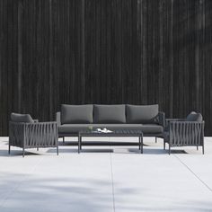 a couch and chair sitting next to each other in front of a wooden wall with vertical slats on it