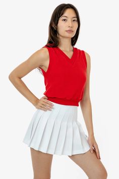 a woman in a red top and white skirt posing for the camera with her hands on her hips