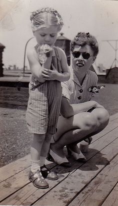 an old black and white photo of two children on a dock, one holding a doll