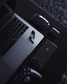 an open laptop computer sitting on top of a black table next to other electronic devices