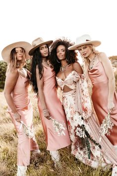 three women in dresses and hats posing for the camera