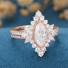 a close up of a diamond ring on a blue surface with flowers in the background