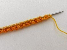 an orange crochet hook with yellow thread