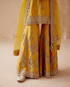 Editor's Note Introducing a stunning mustard kurta sharara adorned with intricate gold floral thread embroidery, elegantly highlighted with various embellishments. This captivating ensemble is ... Eid Palazzo Set With Gold Embroidery And Straight Kurta, Chinon Sharara With Gota Work And Straight Kurta, Chinon Sharara With Gota Work, Sharara With Gota Work And Straight Kurta In Chinon, Diwali Sharara In Chinon With Traditional Drape, Yellow Anarkali Palazzo Set For Eid, Festive Palazzo Set With Gold Embroidery For Eid, Gold Chanderi Palazzo Set With Traditional Drape, Yellow Sharara With Resham Embroidery And Straight Kurta