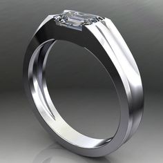 a white gold ring with an emerald cut diamond in the center, on a grey background