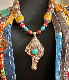 "Tibetan Nepalese handmade turquoise huge repousse conch vintage pendant amulet with beautiful Tibetan capped copal Nepalese beads unique bohemian statement necklace. This is a large chunky necklace that is bold and beautiful and guaranteed to make a statement! This necklace measures 26\" in length.  Beautiful handmade vintage beads from nepal beaded with a focal handmade Tibetan turquoise repousse conch amulet silver pendant.  The conch turquoise amulet is big and measures 3.5\" in height and 2\" in width. It has 20mm big blue Cabochon turquoise in the center.   There are multiple different size and style capped silver Tibetan beads ranging in size from 14mm up to 26mm.   This piece is finished with a large Tibetan antique silver double hook clasp closure. You will get the exact pictured Traditional Turquoise Necklace With Natural Stones For Festivals, Bohemian Large Pendant Necklace From Vintage Collection, Artisan Turquoise Necklace With Large Beads For Festival, Traditional Carved Necklaces For Festival, Bohemian Multicolor Necklaces For Vintage Collection, Bohemian Multicolor Necklace Vintage, Handmade Traditional Turquoise Necklace For Festivals, Bohemian Multicolor Turquoise Necklace With Large Pendant, Bohemian Turquoise Necklace With Large Multicolor Pendant