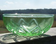 a green glass bowl sitting on top of a wooden table