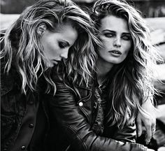 two beautiful young women sitting next to each other on a motorcycle seat in black and white