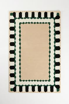 an area rug with black, white and green designs on the bottom in front of a wall