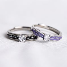 two wedding rings sitting on top of each other with diamonds in the middle and purple accents