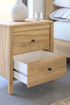 a wooden nightstand with two drawers and a white vase on top of the night stand