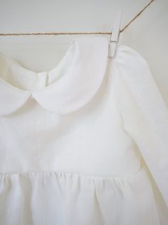 a white dress hanging on a clothes line with a string attached to the back of it