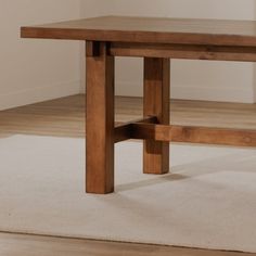 a wooden table sitting on top of a carpeted floor next to a white rug