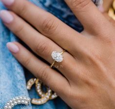 a close up of a person's hand wearing an engagement ring