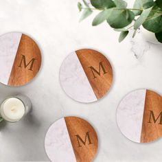 three coasters with the letter m on them next to a candle and some flowers