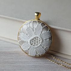 This vintage lace necklace is the perfect gift for those that love a timeless and elegant style. The European cotton flower lace evokes a sense of delicate beauty, with a background of shiny cream color satin that highlights the intricate lace design. It's set in a gold metallic metal alloy pendant, with a dainty gold stainless steel chain that measures 22 inches in total length. Gift box: The necklace will be packaged in a stylish, branded gift box, ready to be presented with love and care.  Gift notes:  Write a personalized note to your loved one at checkout, and it will be printed on decorative paper and placed in the box. Details: Pendant - 1.5 inches across (4 cm). Pendant backing material - bright gold alloy (hypoallergenic and nickel-free).  Chain - gold stainless steel with lobster Elegant Beige Necklaces For Wedding, Elegant Beige Necklace For Wedding, Delicate Cream Jewelry As A Gift, Delicate Cream Jewelry For Gift, Adjustable Cream Necklace For Wedding, Elegant White Necklace For Wedding Gift, Vintage White Necklace For Anniversary, Classic Wedding Necklaces With Flower Shape, White Round Necklace For Wedding Gift