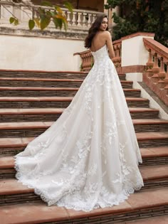 a woman in a wedding dress standing on some steps with her back to the camera