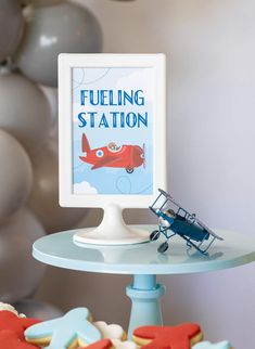 a small toy airplane sitting on top of a table next to a sign that says fueling station