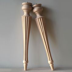 two wooden candlesticks sitting next to each other on top of a shelf in front of a gray wall