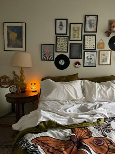 there is a bed with many pictures on the wall above it and a lamp next to it