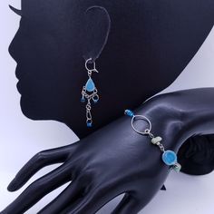 "A darling glass bead and silvertone link bracelet and dangle earrings set in shades of silver, blue and black, Bracelet is adjustable. Earrings measure 2.5 x 1\" Bracelet is 7\" long, adjustable to smaller sizes. US SHIPPING: US orders over $35 or for 3 or more items ship free via first class mail. Orders over $150 receive a free priority mail upgrade. Expedited shipping is available. SHIPPING OUTSIDE THE US: We combine shipping on multiple item orders. Expedited shipping is available. Enter co Adjustable Dangle Costume Jewelry, Turquoise Nickel-free Czech Glass Jewelry, Nickel-free Turquoise Czech Glass Jewelry, Blue Metal Jewelry With Lobster Clasp, Adjustable Czech Glass Jewelry Bracelet, Czech Glass Bracelet Jewelry, Adjustable Bohemian Jewelry With Silver Plated Wire, Adjustable Bohemian Silver Plated Jewelry, Bohemian Adjustable Silver Plated Jewelry