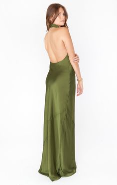 a woman in a green dress with her back turned to the camera and looking down