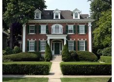 a red brick house with green shutters and white trim