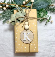 a gift wrapped in brown paper with a monogrammed letter k on it and tied up with twine