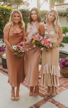 three bridesmaids pose for the camera with their bouquets in front of them