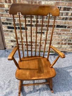 a wooden rocking chair sitting in front of a brick wall