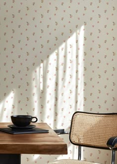 a wooden table with a black bowl on top of it next to a wall paper