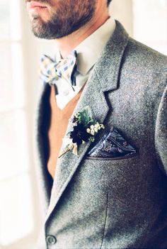 a man wearing a gray suit with a bow tie and flower boutonniere