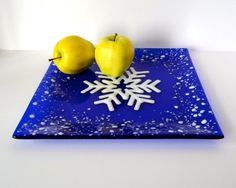 two apples sitting on top of a blue plate with snowflakes and an apple