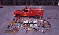 a red truck with tools and other items on the floor in a parking lot next to it