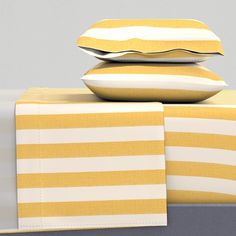 two yellow and white pillows stacked on top of each other next to a pillow case