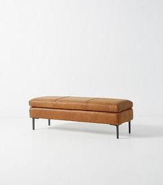 a tan leather bench sitting on top of a white floor