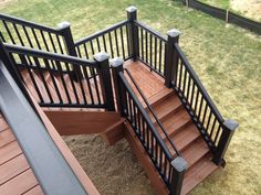 a wooden staircase with black railing and handrails on the side of a house