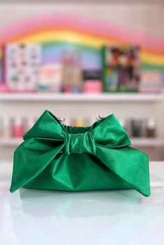 The Mimi Bow Clutch in Kelly Green is super lightweight and large enough to hold all your essentials. Featuring a satin fabric, a statement bow, a magnetic closure, and a detachable gold shoulder strap chain, this bag is perfect for a brunch, or evening out on the town. Handmade in Charleston, South Carolina by Mimi's mom, Keiko! This listing is for one 5" x 9”x 3” clutch. Party Clutch Bags With Bow Detail, Party Clutch Bags With Bow, Rectangular Shoulder Bag With Detachable Bow For Party, Rectangular Bag With Bow For Events, Rectangular Event Bag With Bow Detail, Rectangular Event Bag With Bow, Chic Evening Shoulder Bag With Bow, Clutch Bag With Bow For Events, Event Clutch Bag With Bow Detail