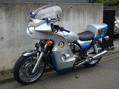 a silver and blue motorcycle parked next to a wall