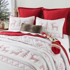 a bed covered in red and white sheets with reindeer decorations on the pillowcases