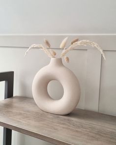 a white vase sitting on top of a wooden shelf