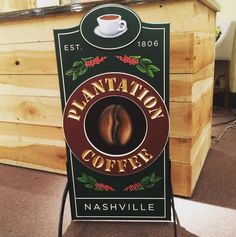 a sign that says plantation coffee in front of a wooden counter with a cup of coffee on it