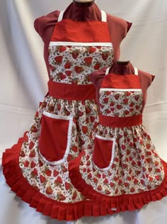 two aprons with red and white flowers on them, one has an apron over the other