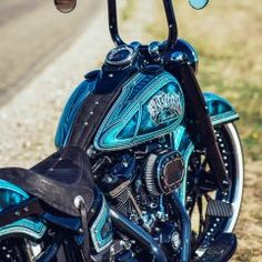 a blue motorcycle parked on the side of a road next to a grass covered field