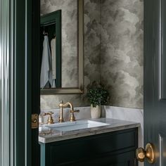 a bathroom sink sitting under a mirror next to a green door with gold faucets